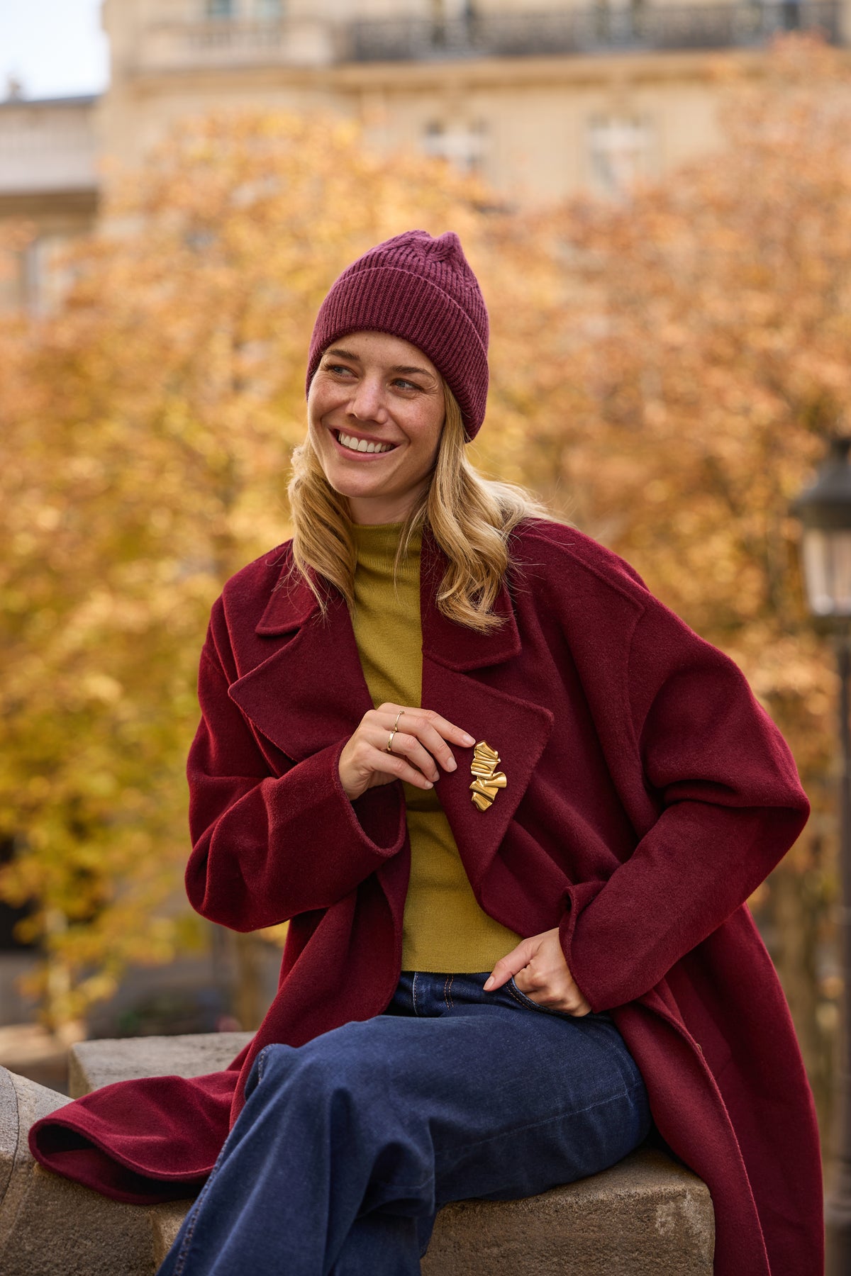 Kate Gold magnetic brooch worn on a burgundy coat in an autumn Paris portrait.